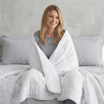 A WOMAN WRAPPED IN WHITE COTTON WEIGHTED BLANKET